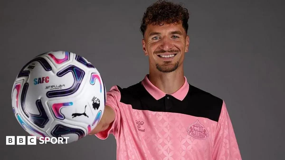 Player holding a football and smiling for camera Player holding a football and smiling for camera