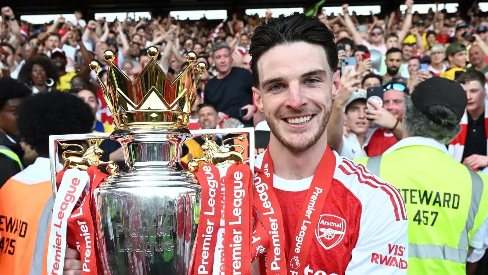 Player holding Premier League trophy with fans celebrating Player holding Premier League trophy with fans celebrating