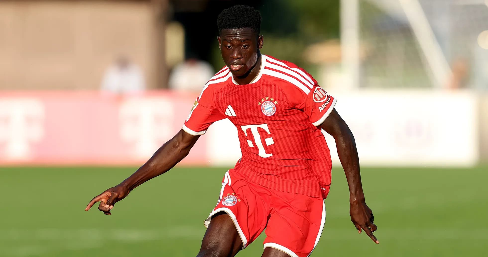 Player in red Bayern Munich kit running on field Player in red Bayern Munich kit running on field
