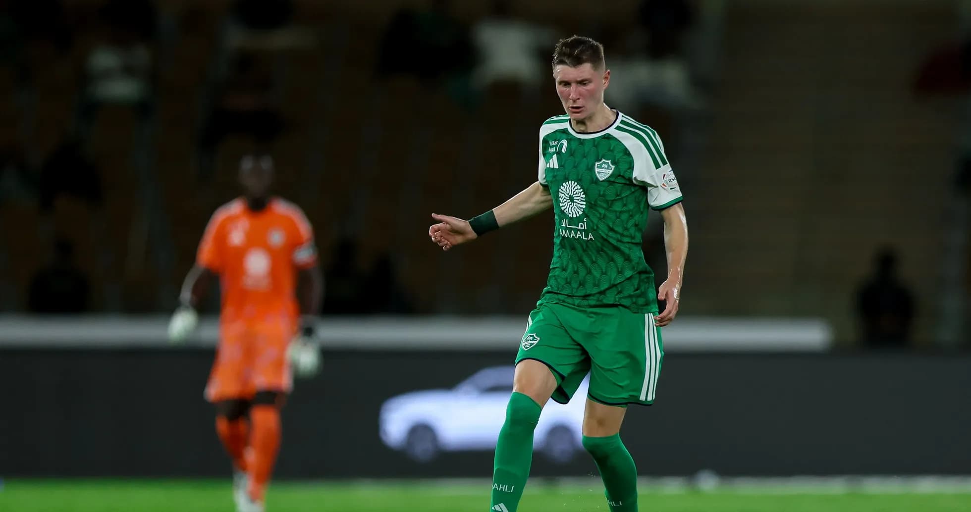 Player in green kit dribbling the ball on field Player in green kit dribbling the ball on field