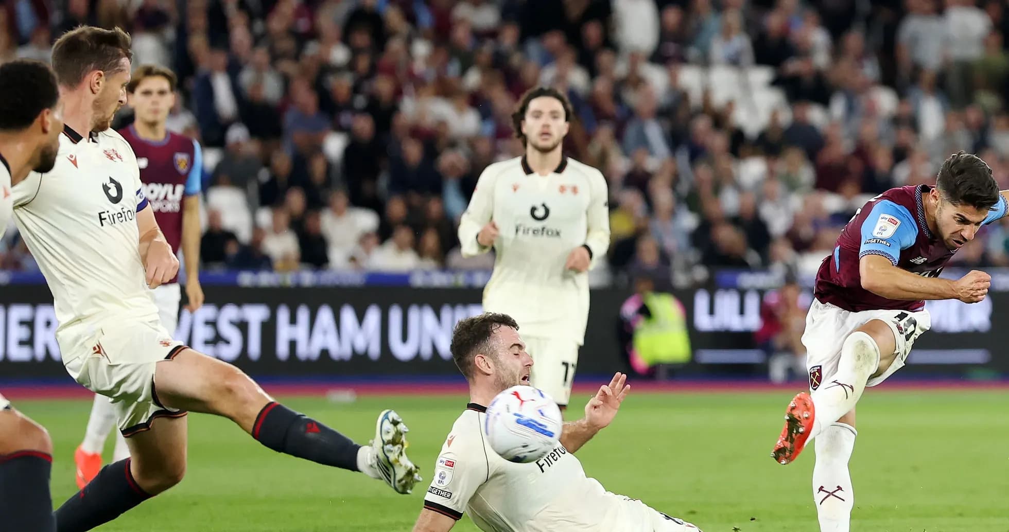 Player kicking ball while opponent falls during match Player kicking ball while opponent falls during match
