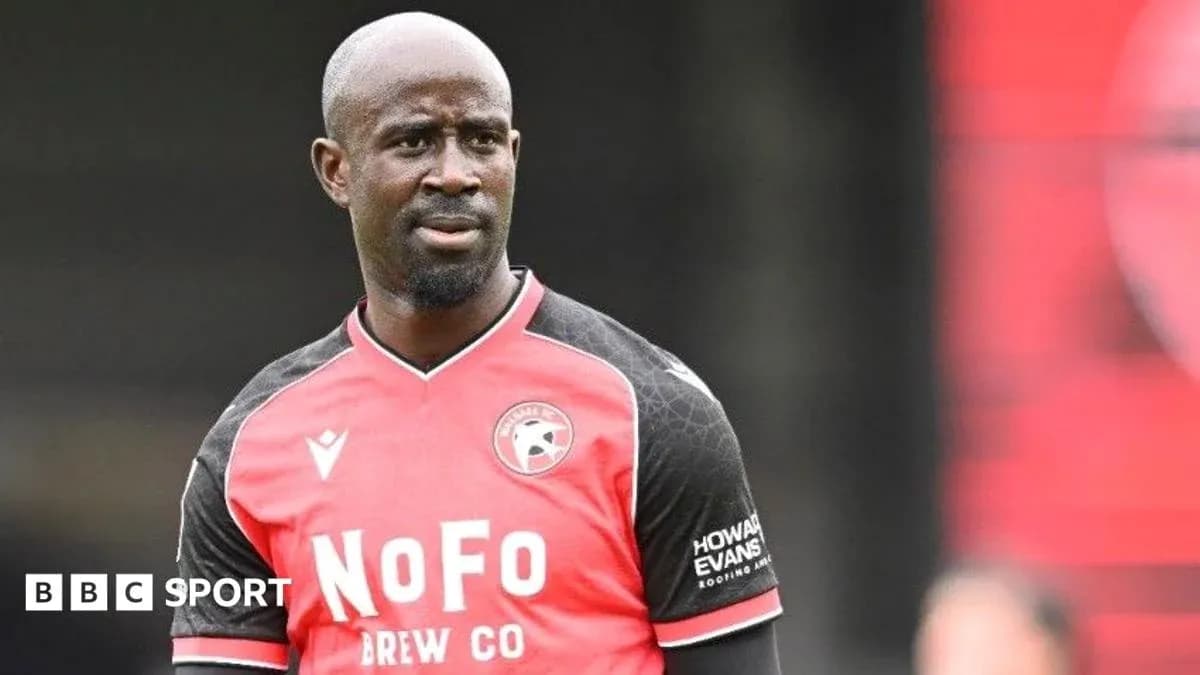Player in red and black kit on the field Player in red and black kit on the field