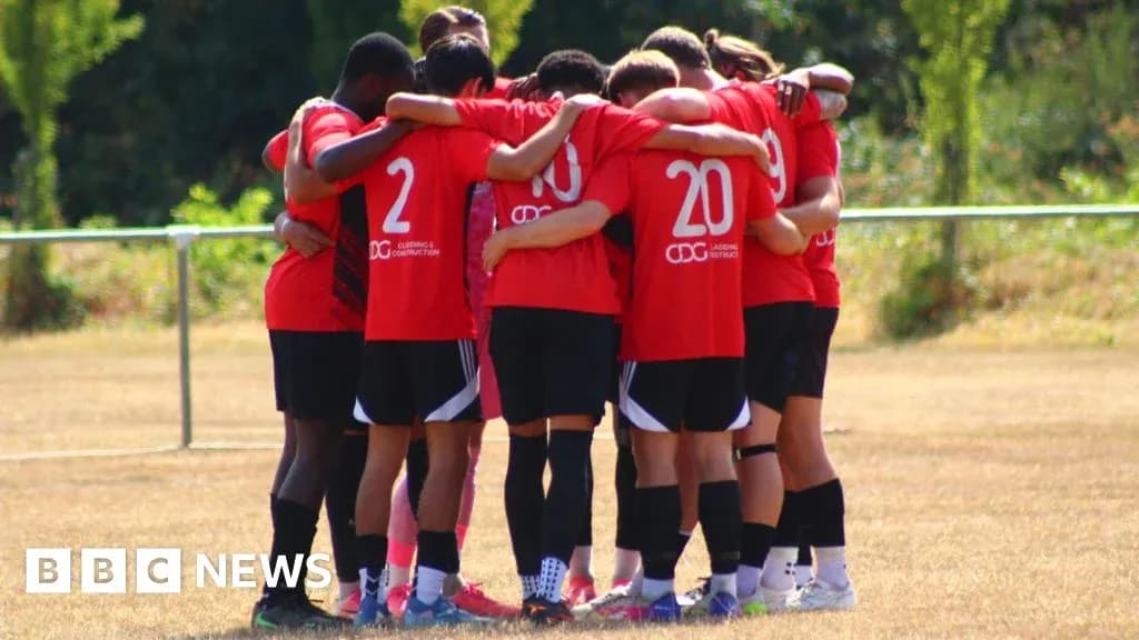 Team huddling together in red jerseys on field Team huddling together in red jerseys on field