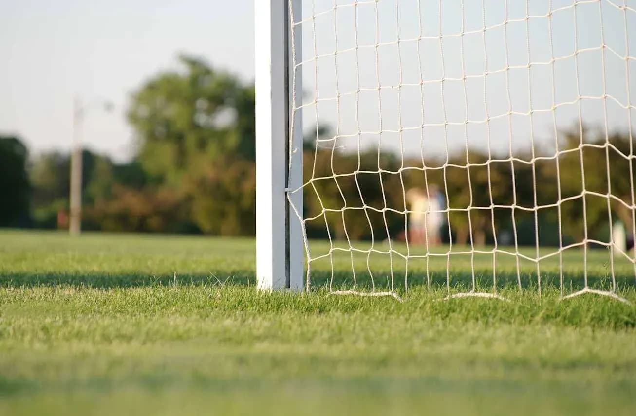 Close-up of soccer goal net on grassy field Close-up of soccer goal net on grassy field