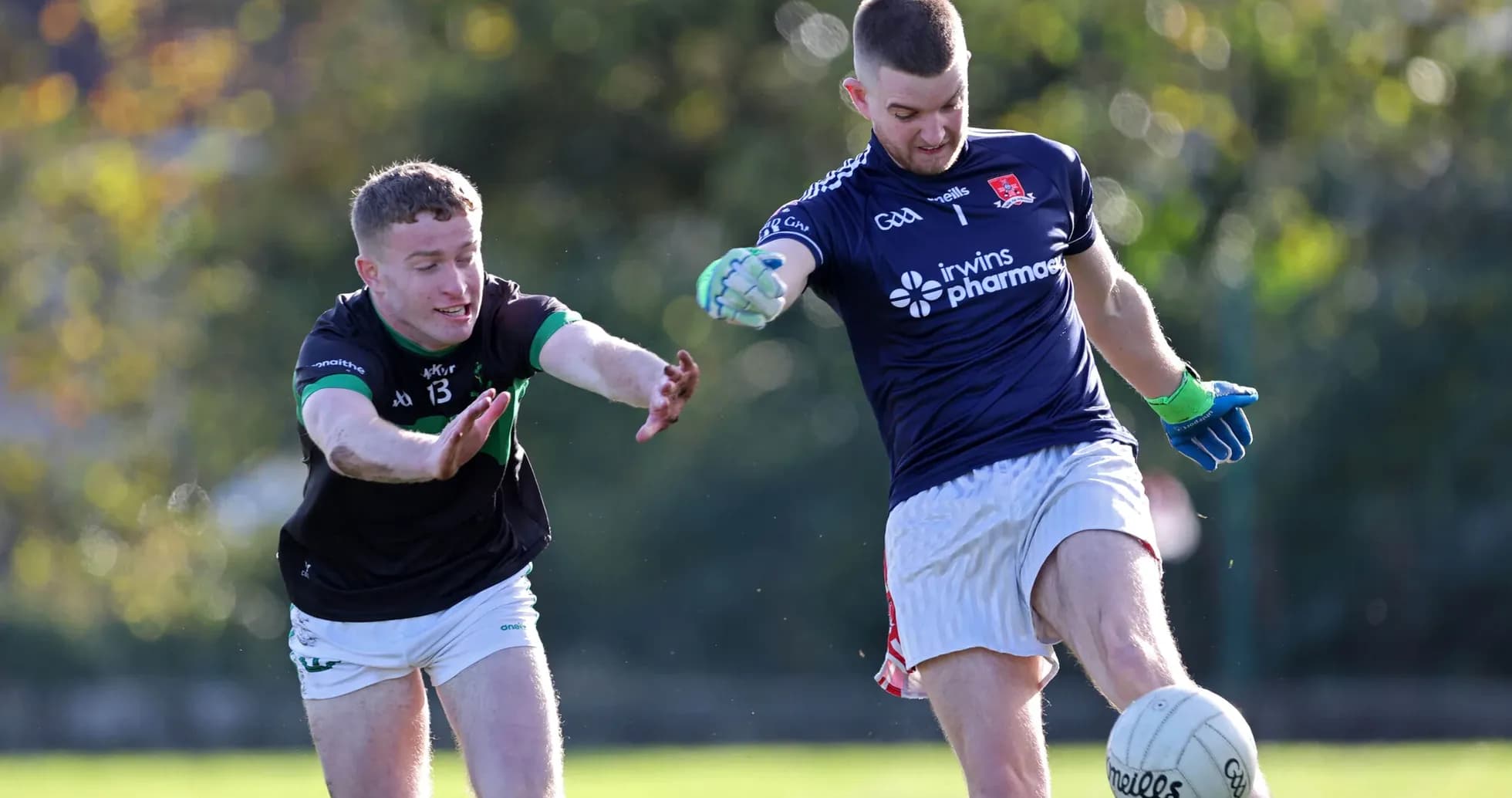 Player kicking the ball while being challenged Player kicking the ball while being challenged