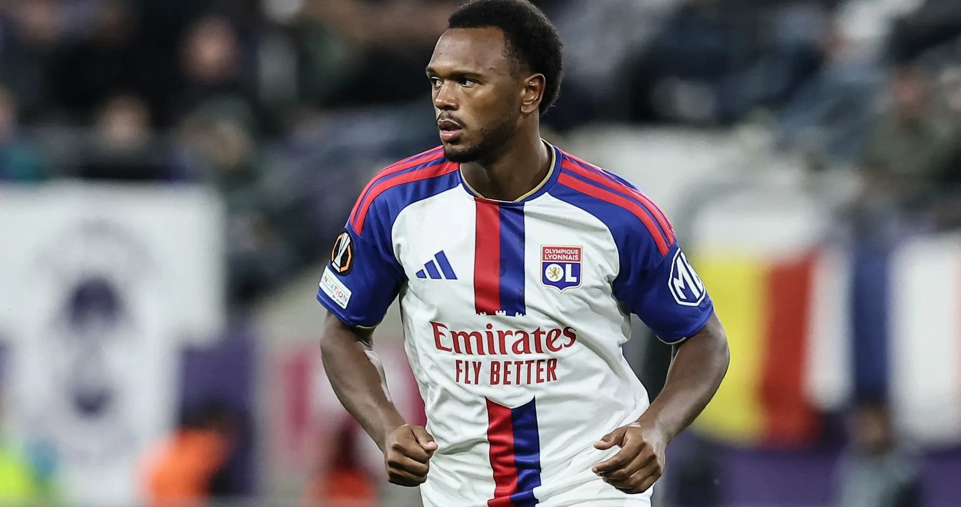 Player in Olympique Lyonnais kit running on field Player in Olympique Lyonnais kit running on field