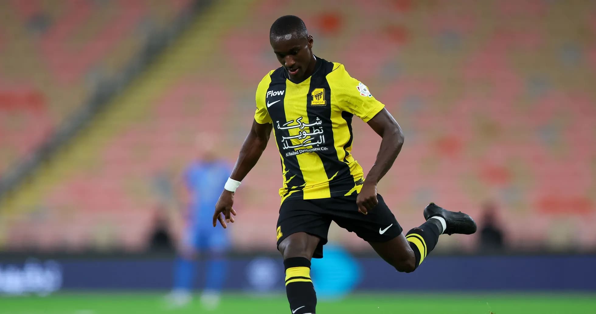 Player in black and yellow kit kicking a soccer ball Player in black and yellow kit kicking a soccer ball
