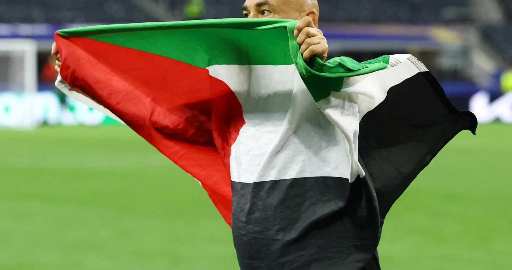 Person holding a Palestinian flag on the field Person holding a Palestinian flag on the field