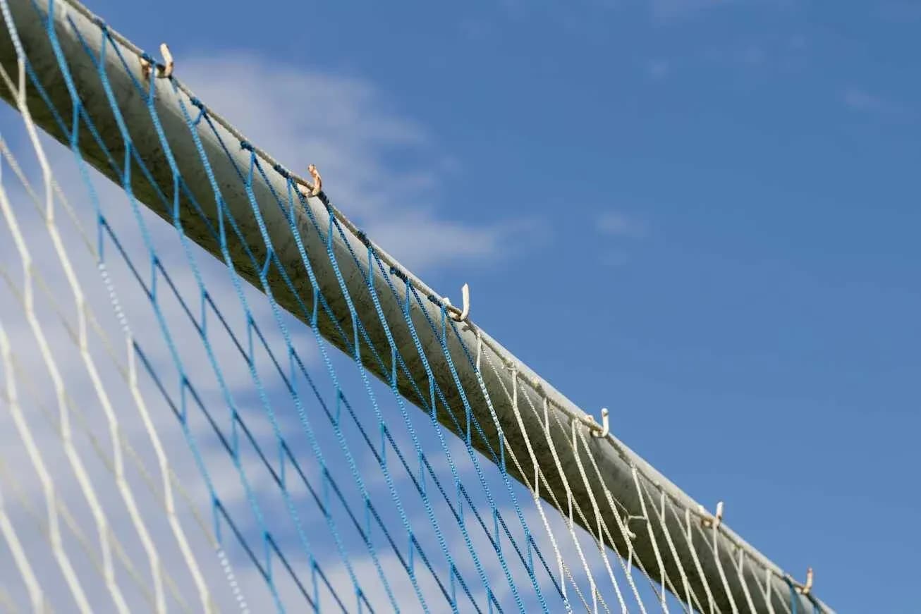 Close-up of a soccer goal net against blue sky Close-up of a soccer goal net against blue sky