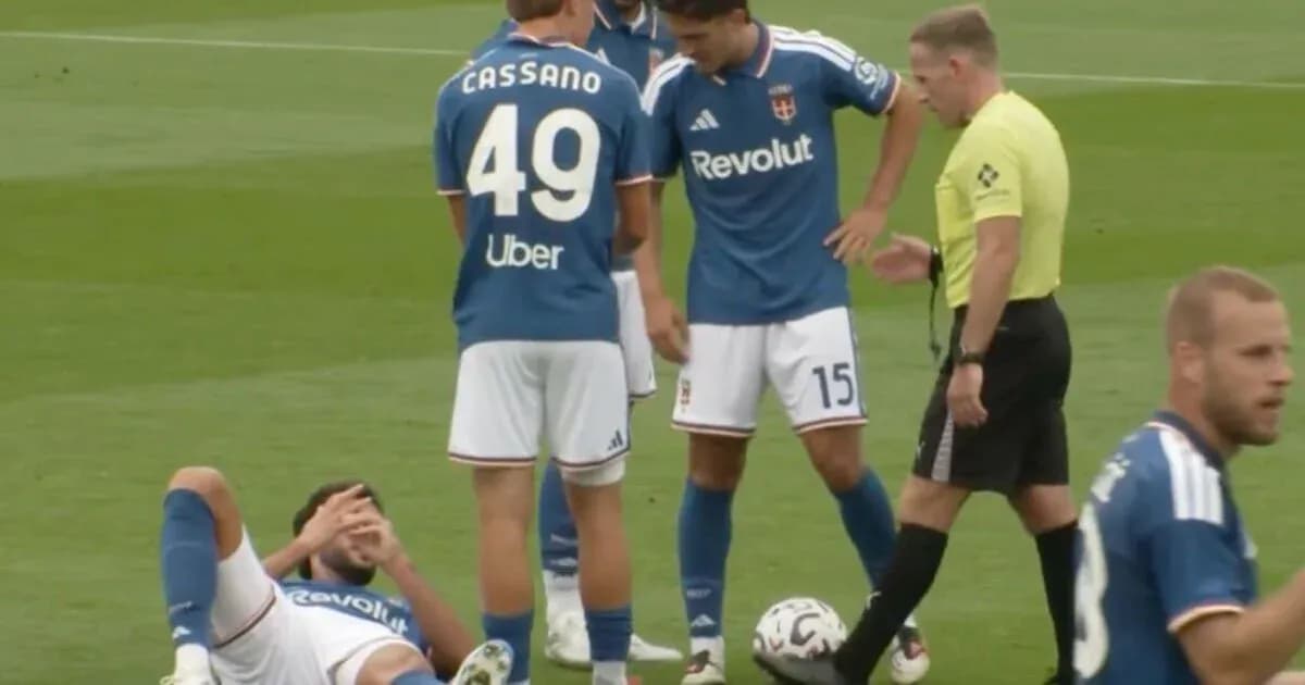 Player down on pitch with teammates and referee nearby Player down on pitch with teammates and referee nearby