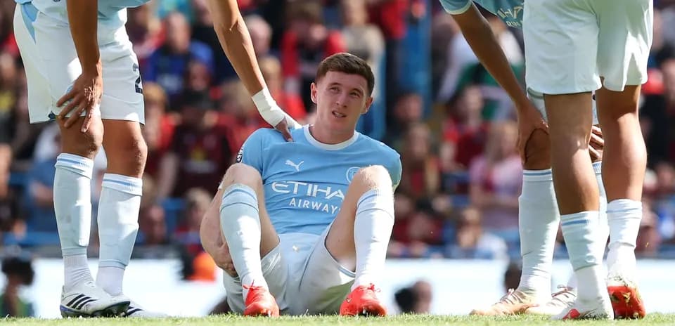 Player sitting on field with teammates nearby Player sitting on field with teammates nearby