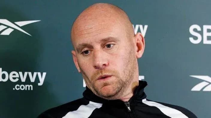 Man speaking at press conference with serious expression Man speaking at press conference with serious expression