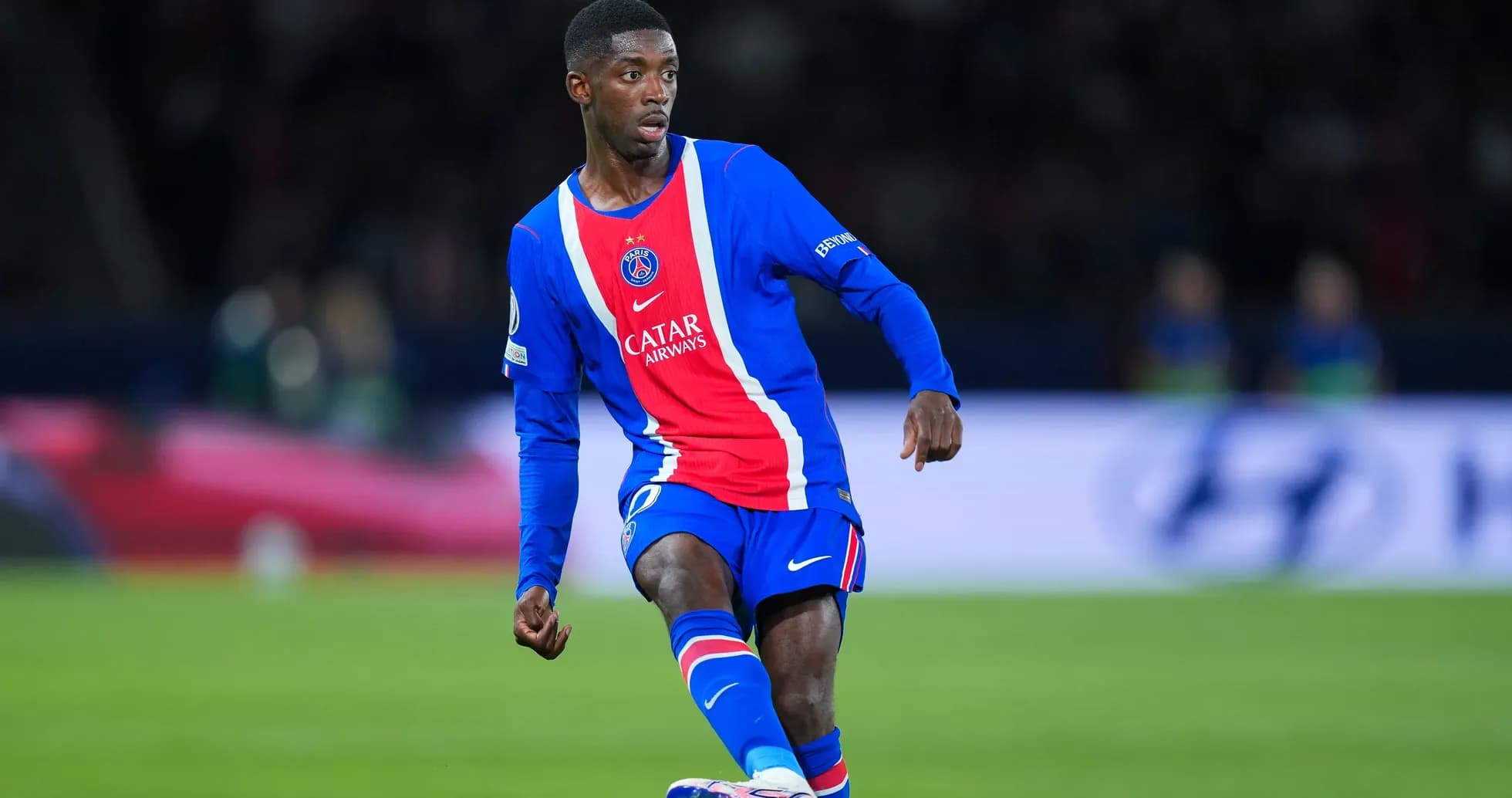 Player in PSG kit dribbling the ball on field Player in PSG kit dribbling the ball on field