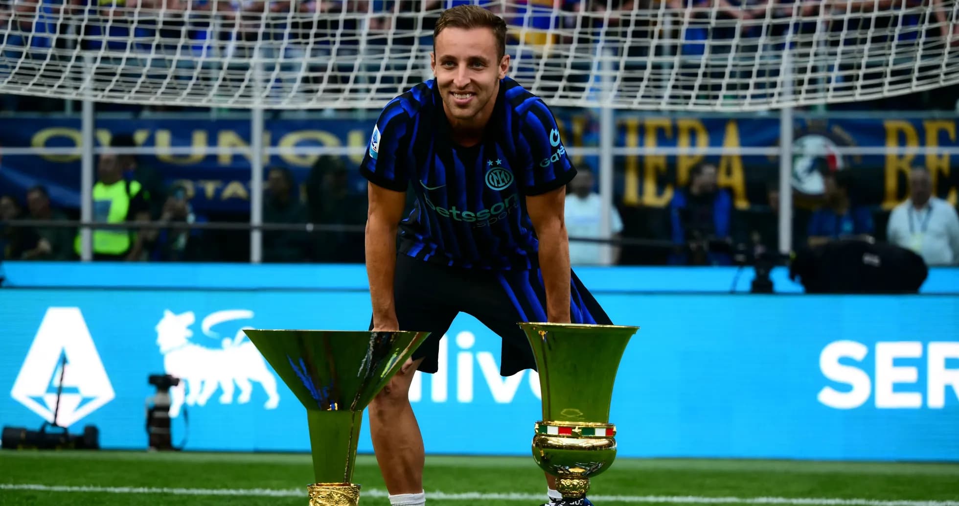 Player posing with two trophies on the field Player posing with two trophies on the field