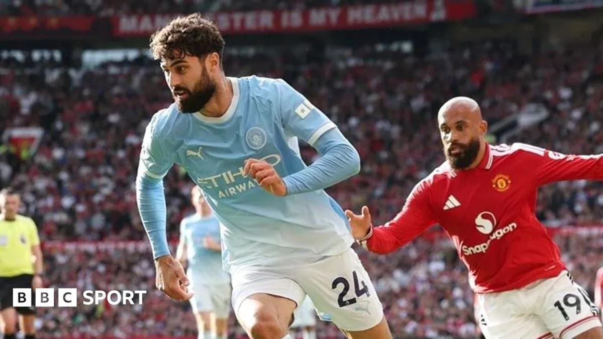 Manchester City player dribbling past Manchester United opponent Manchester City player dribbling past Manchester United opponent