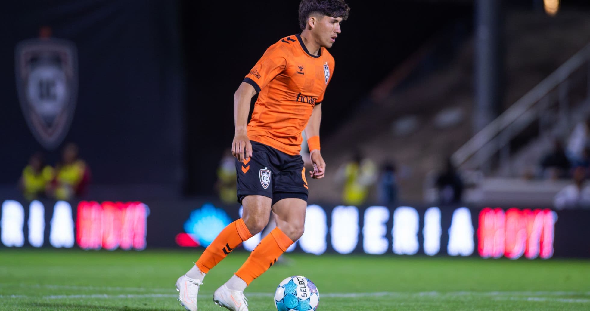 Player in orange kit dribbling the ball Player in orange kit dribbling the ball