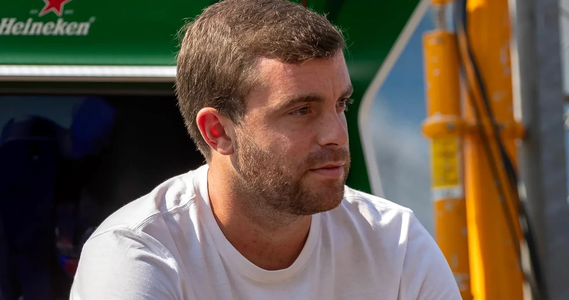 Man in white shirt sitting near racing equipment Man in white shirt sitting near racing equipment