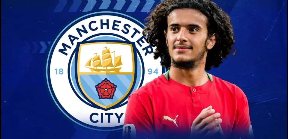 Player in red shirt with Manchester City logo background Player in red shirt with Manchester City logo background