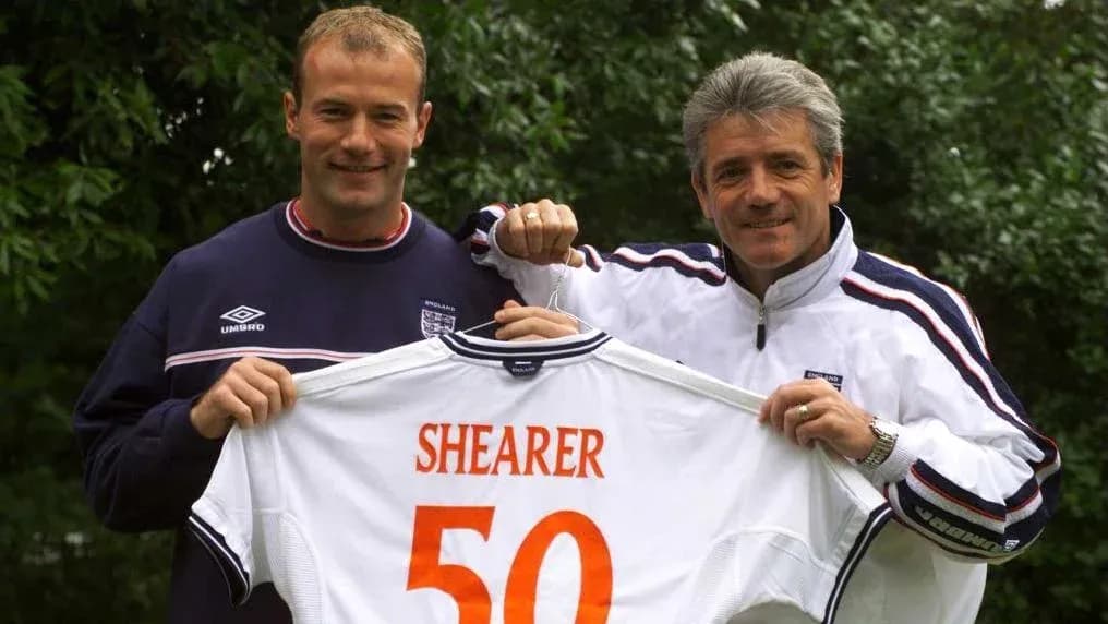 Two men holding an England football shirt with 'SHEARER 50' Two men holding an England football shirt with 'SHEARER 50'