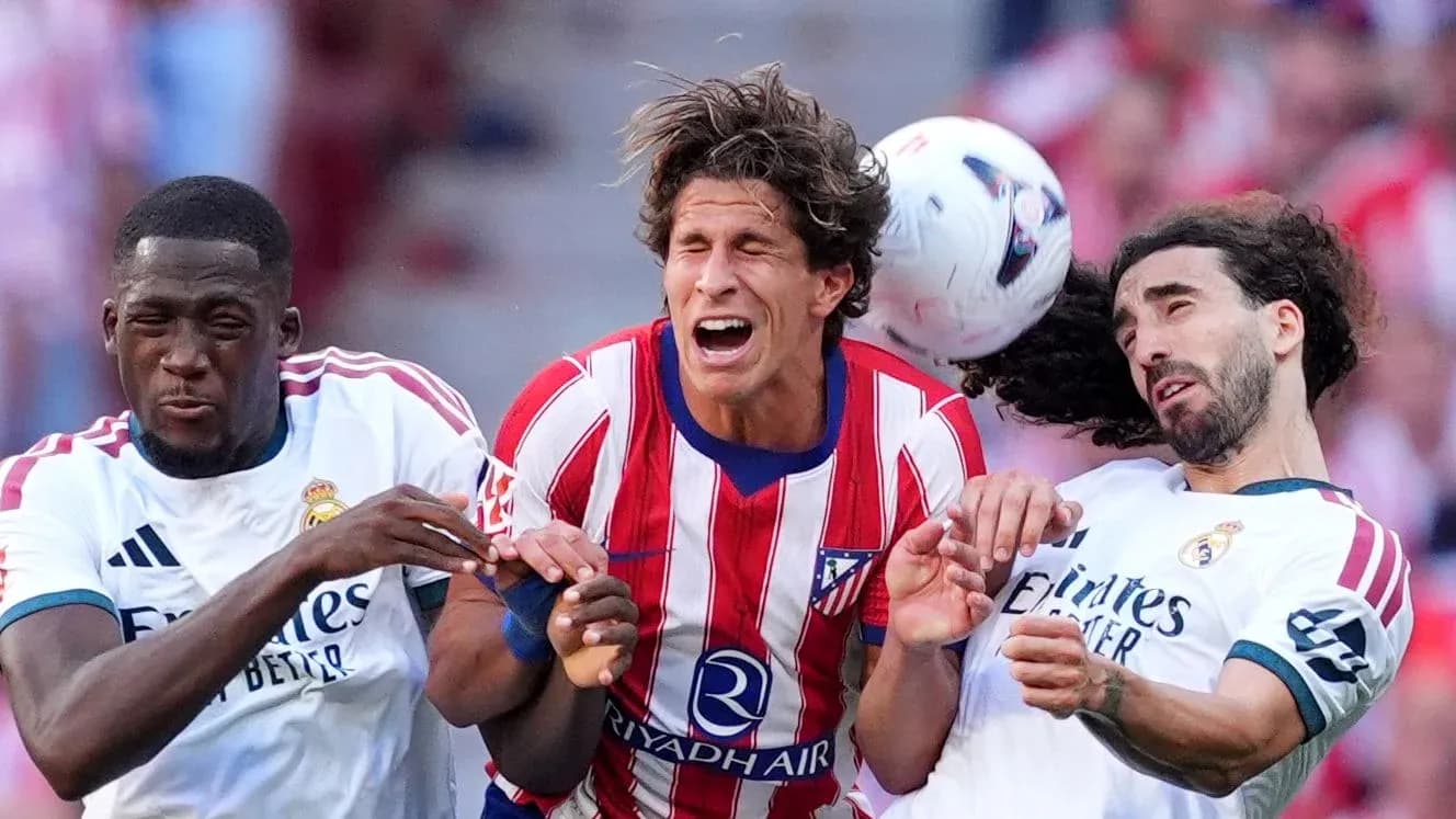Players from Atlético and Real Madrid contesting for the ball Players from Atlético and Real Madrid contesting for the ball