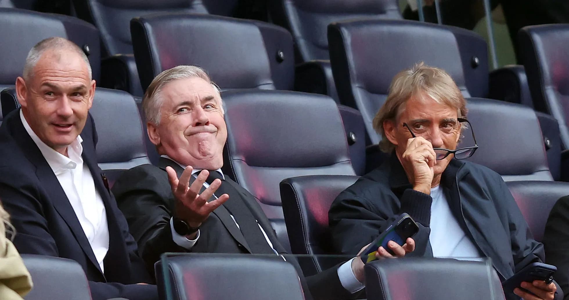 Three men sitting in stadium seats during event Three men sitting in stadium seats during event