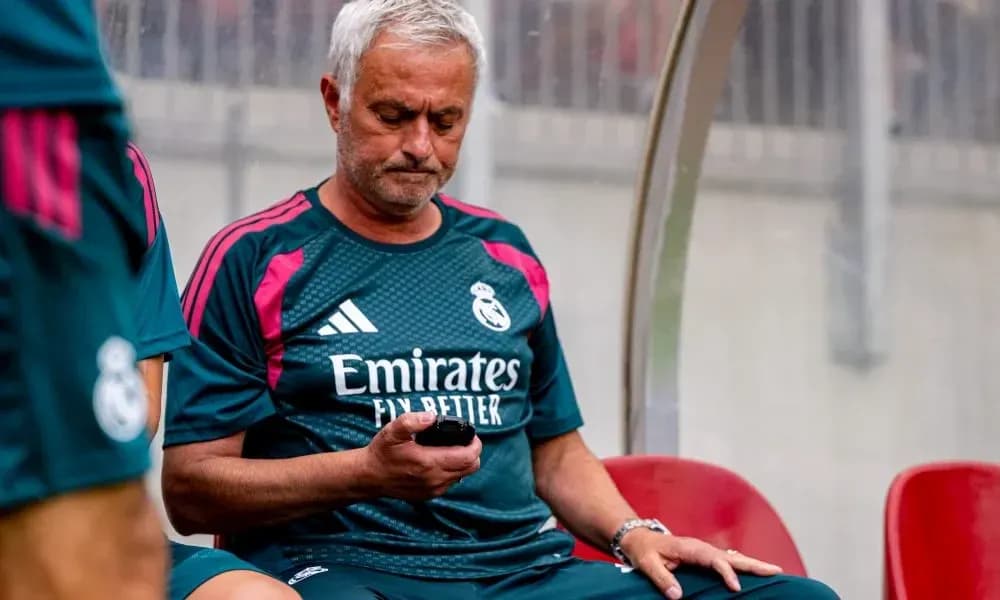 Coach sitting on bench using mobile phone Coach sitting on bench using mobile phone
