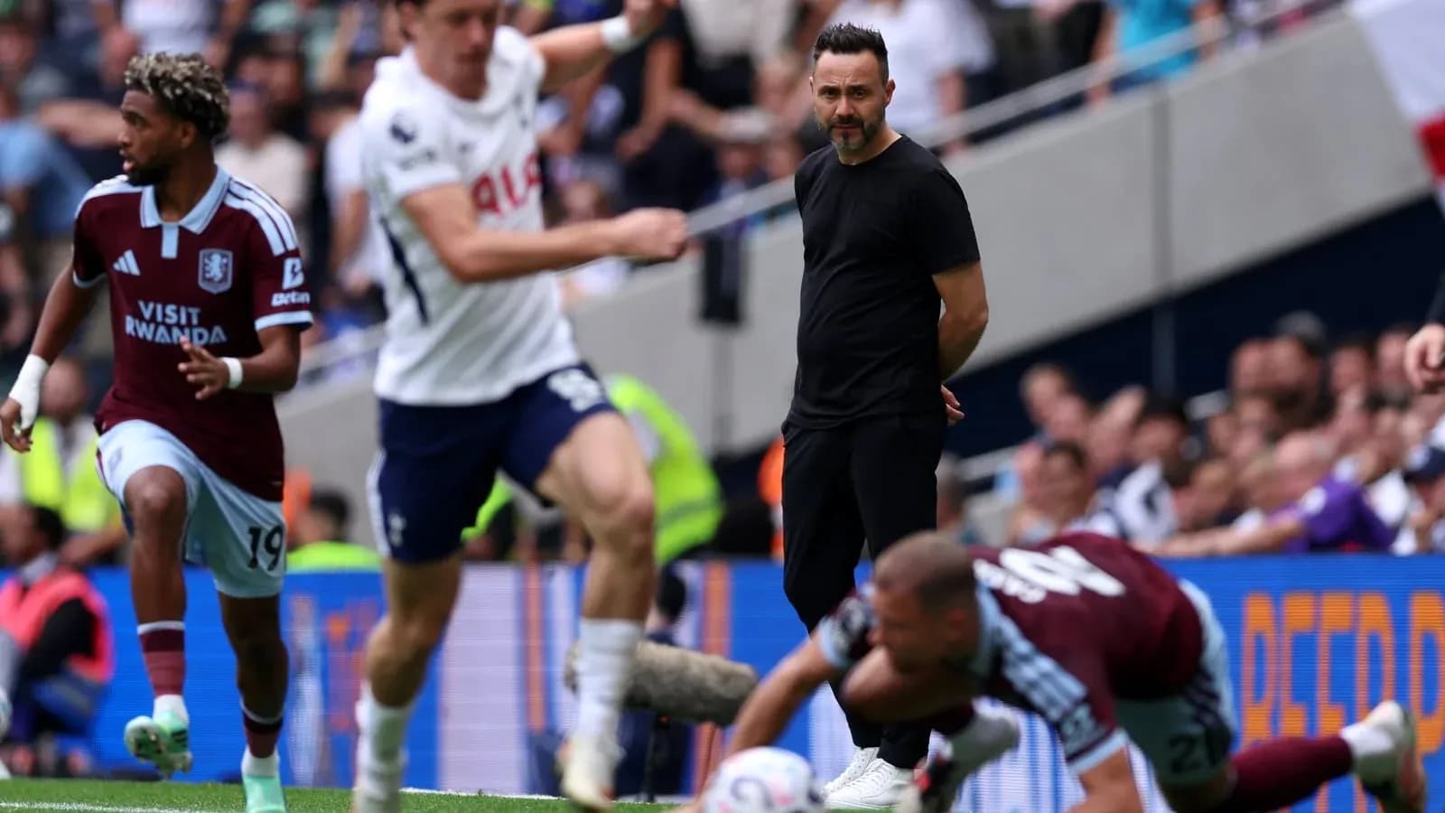 Aston Villa player running during match, coach observing Aston Villa player running during match, coach observing