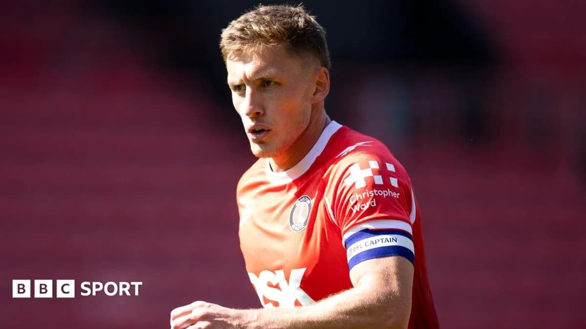 Player in red jersey with captain's armband on pitch Player in red jersey with captain's armband on pitch