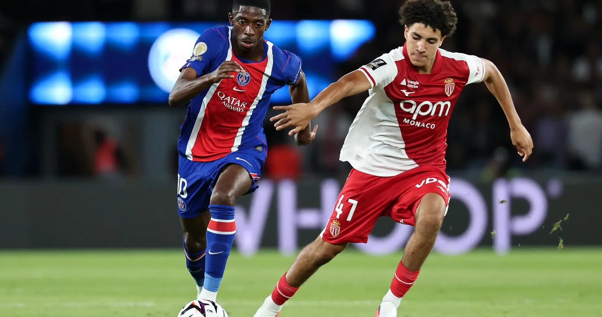 Player in blue and red jersey dribbling past opponent Player in blue and red jersey dribbling past opponent