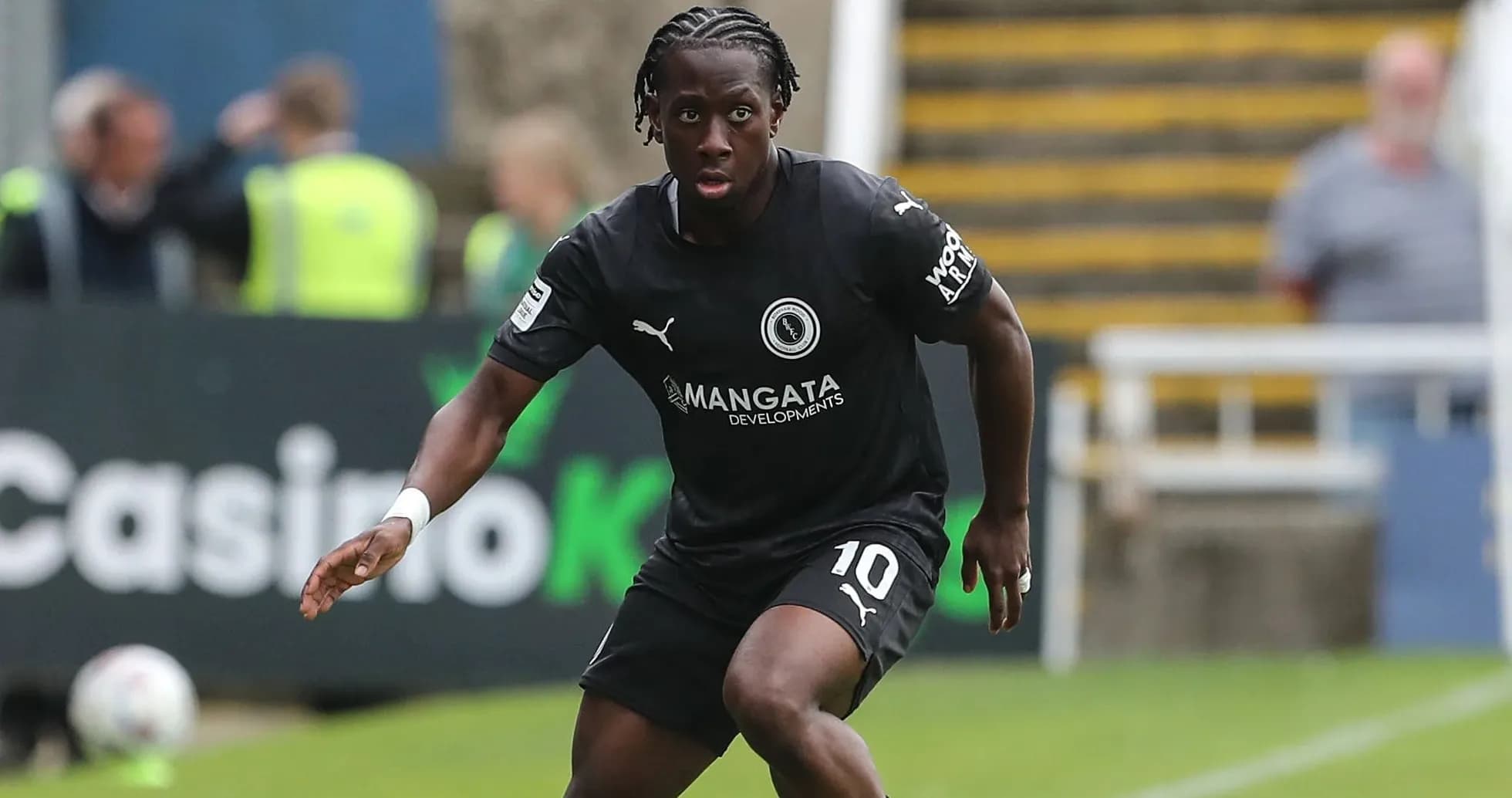 Player in black kit dribbling the ball on field Player in black kit dribbling the ball on field