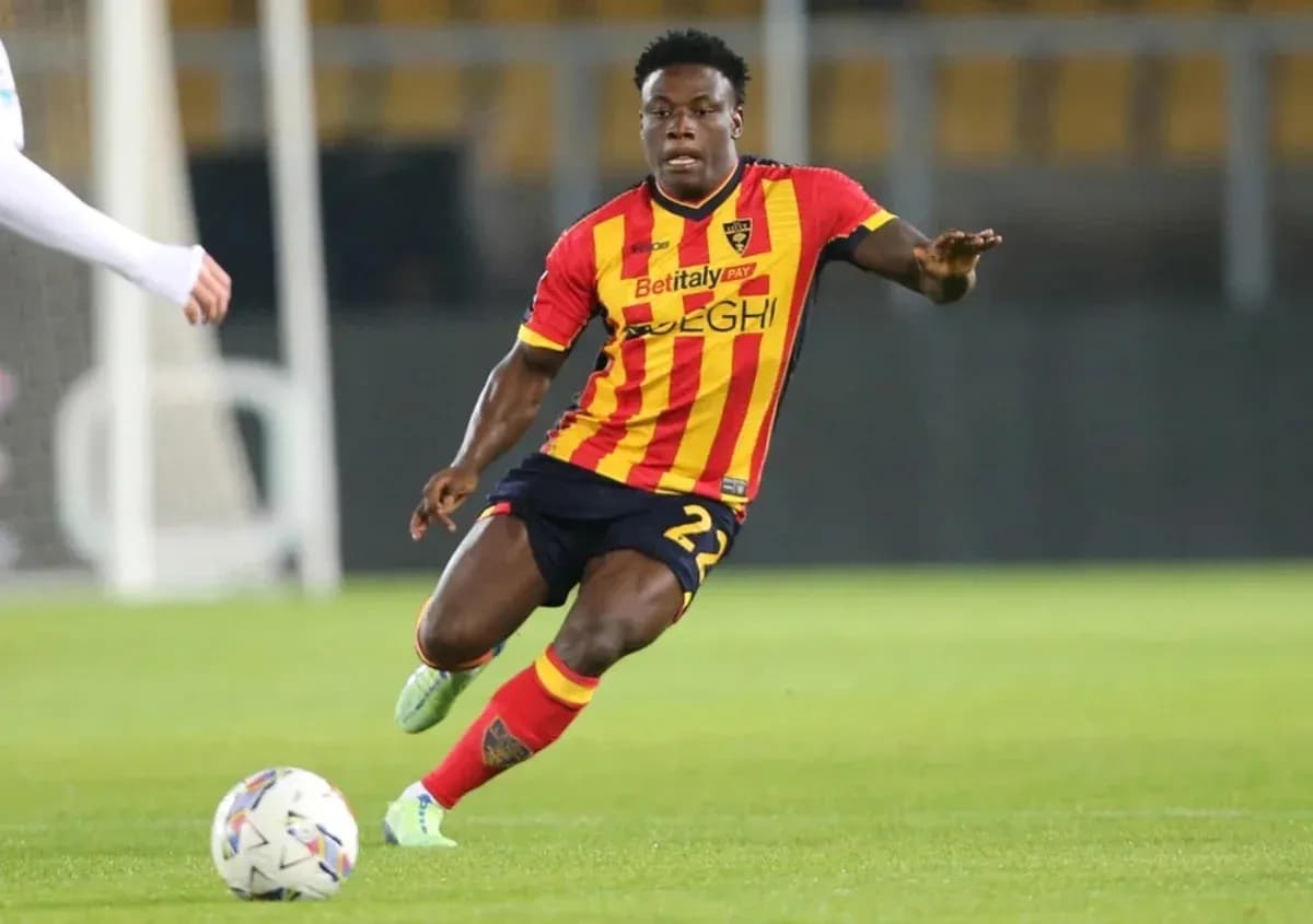 Player in red and yellow jersey dribbling ball on field Player in red and yellow jersey dribbling ball on field