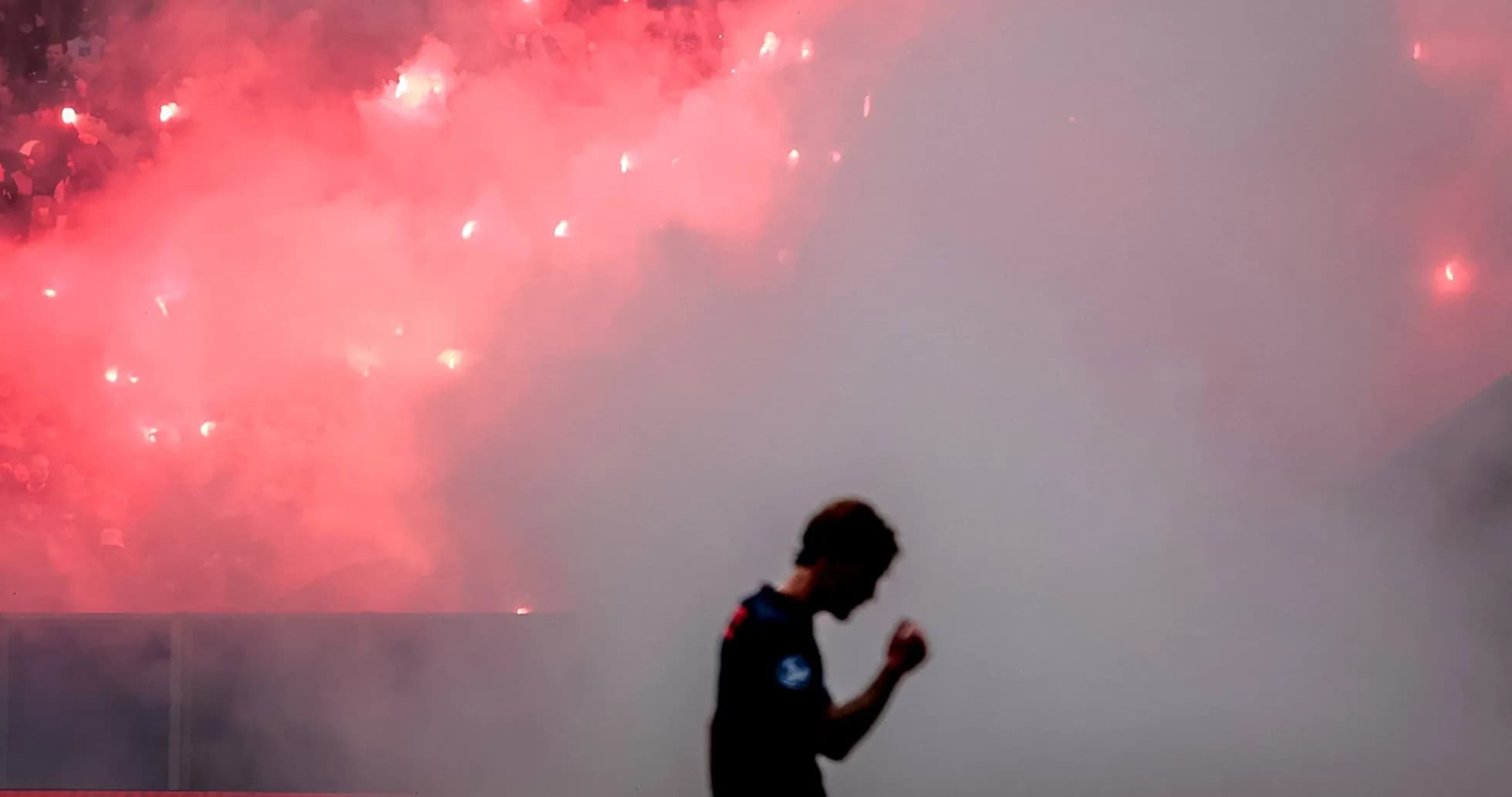Player celebrating amidst smoke and flares in stadium Player celebrating amidst smoke and flares in stadium
